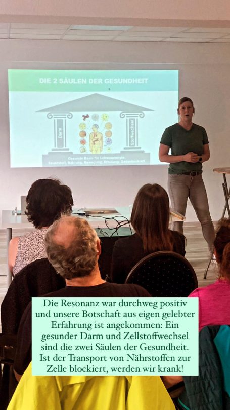 Alexandra Thiery steht vor Leinwand und erklärt einem großen Publikum die drei Säulen der Gesundheit: Darm, Leber und Zellstoffwechsel.